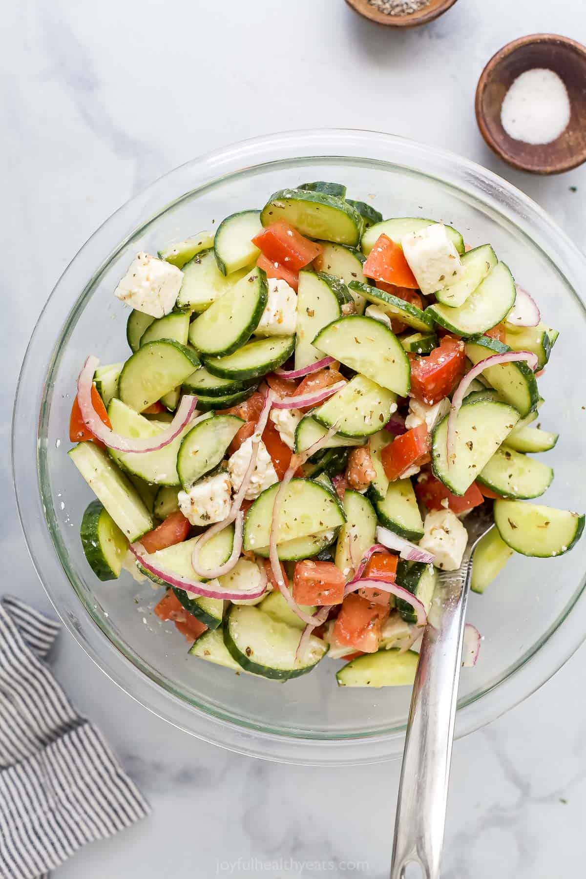 Onions, tomatoes, cucumbers and feta being tossed with red wine vinaigrette