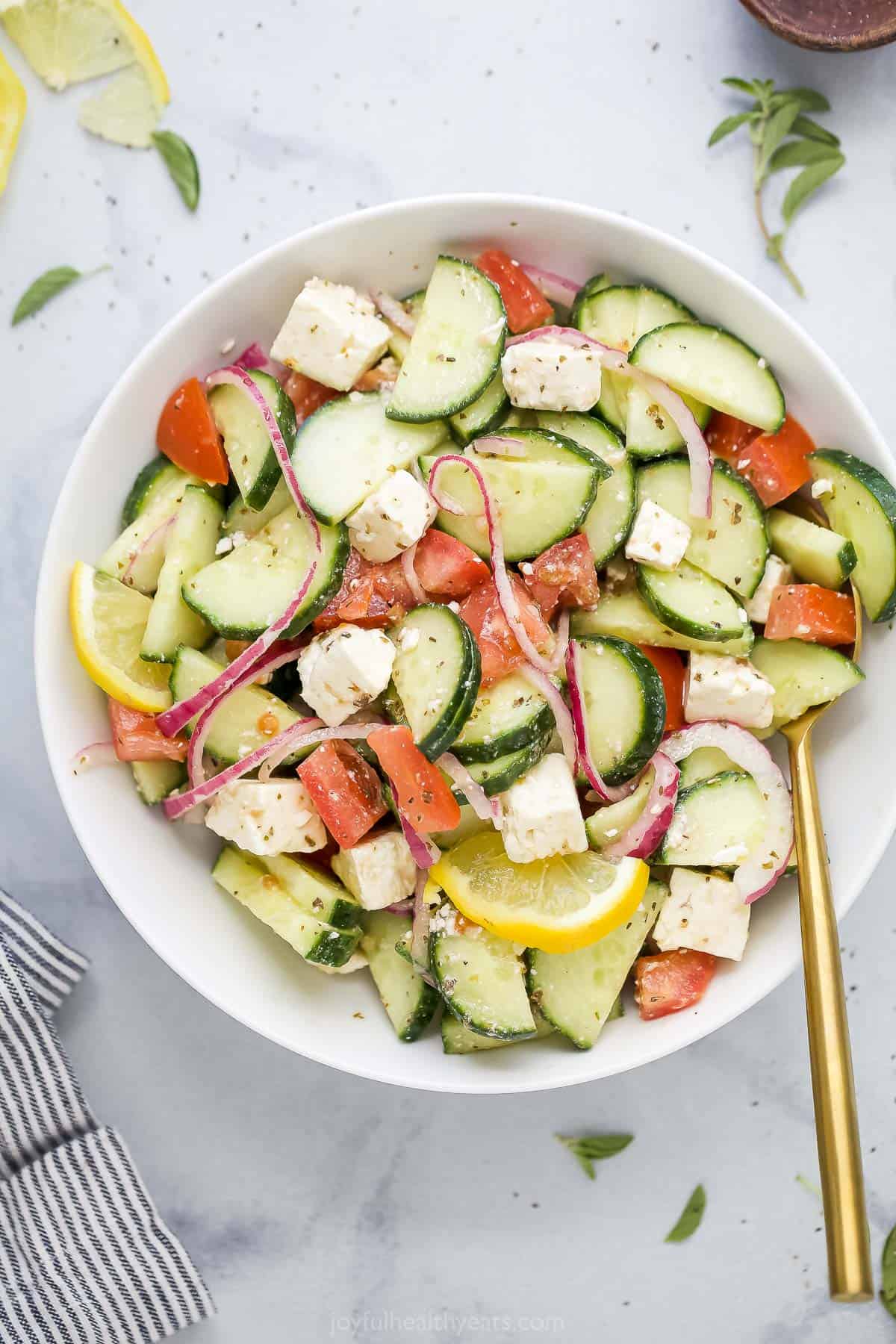 A bowl of Mediterranean salad with a golden spoon inside