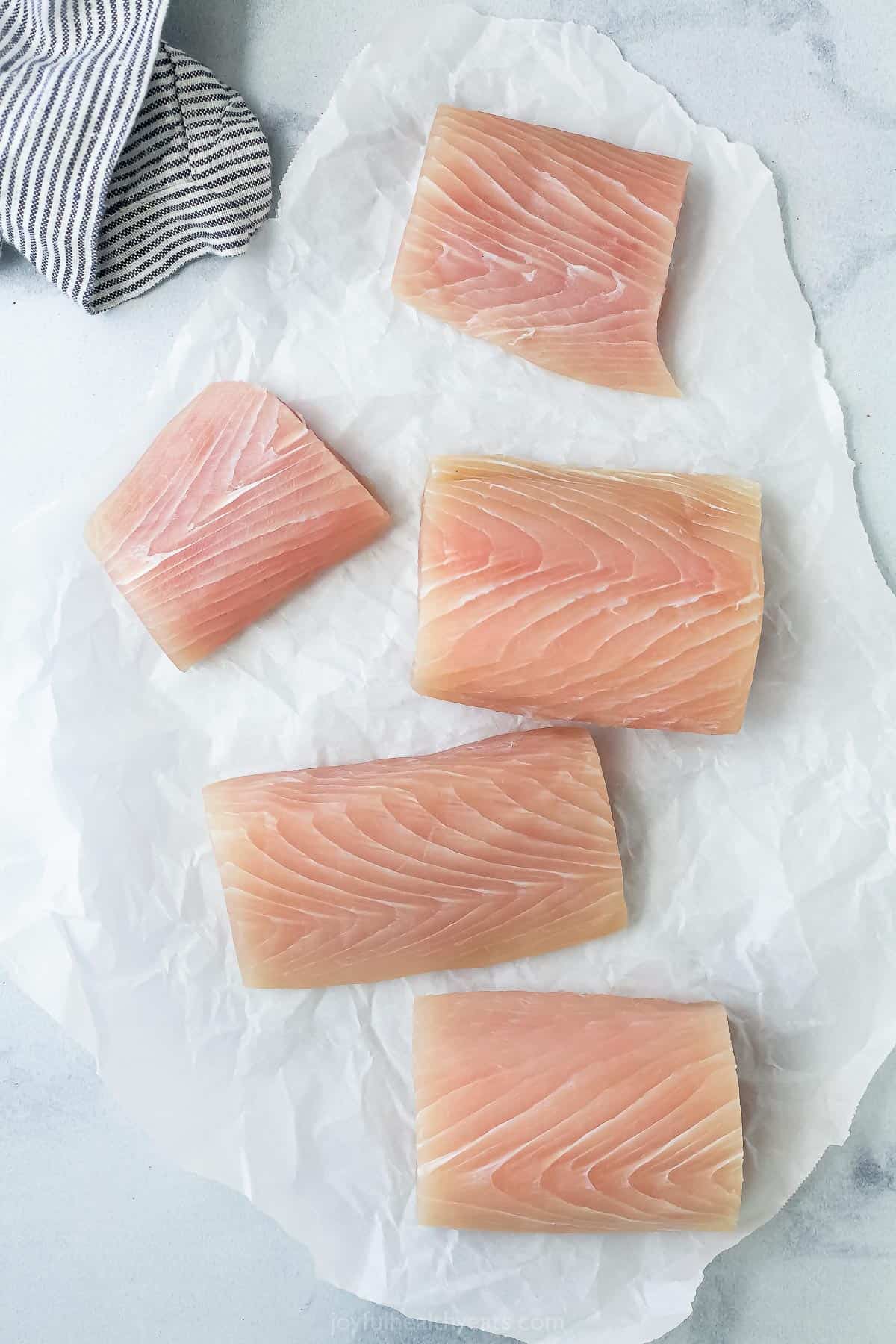 Raw wild-caught mahi mahi fillets on top of a piece of parchment paper