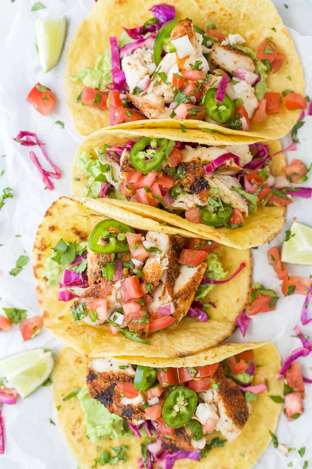 Grilled mahi mahi tacos in soft corn tortillas lined up on a kitchen countertop