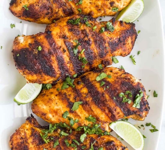Four garlic lime chicken breasts lined up on a long serving platter