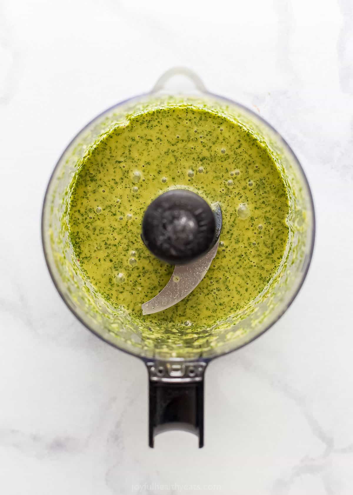 Homemade cilantro lime dressing inside of a food processor on a kitchen countertop