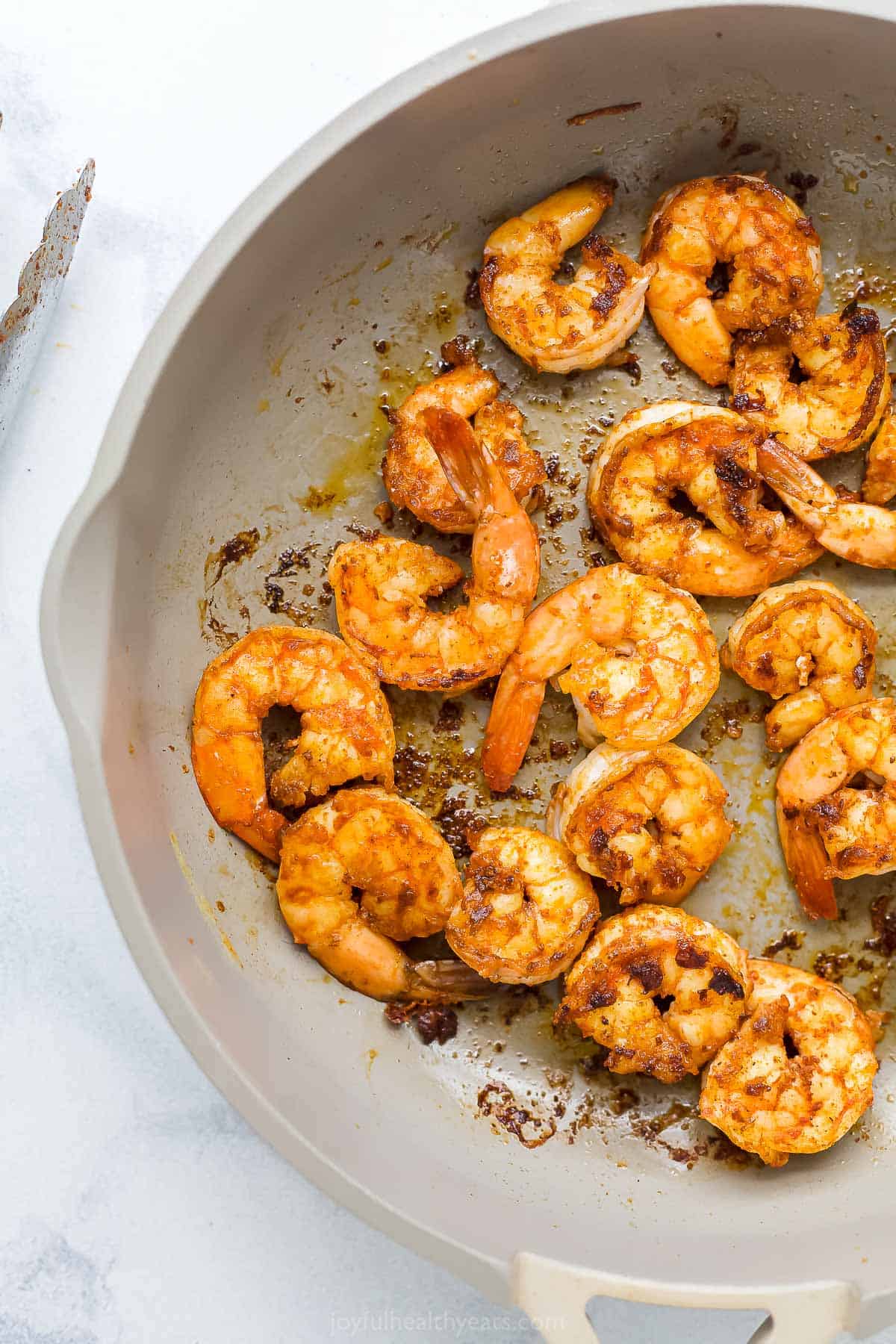 Peeled and deveined shrimp being seared inside of a large skillet