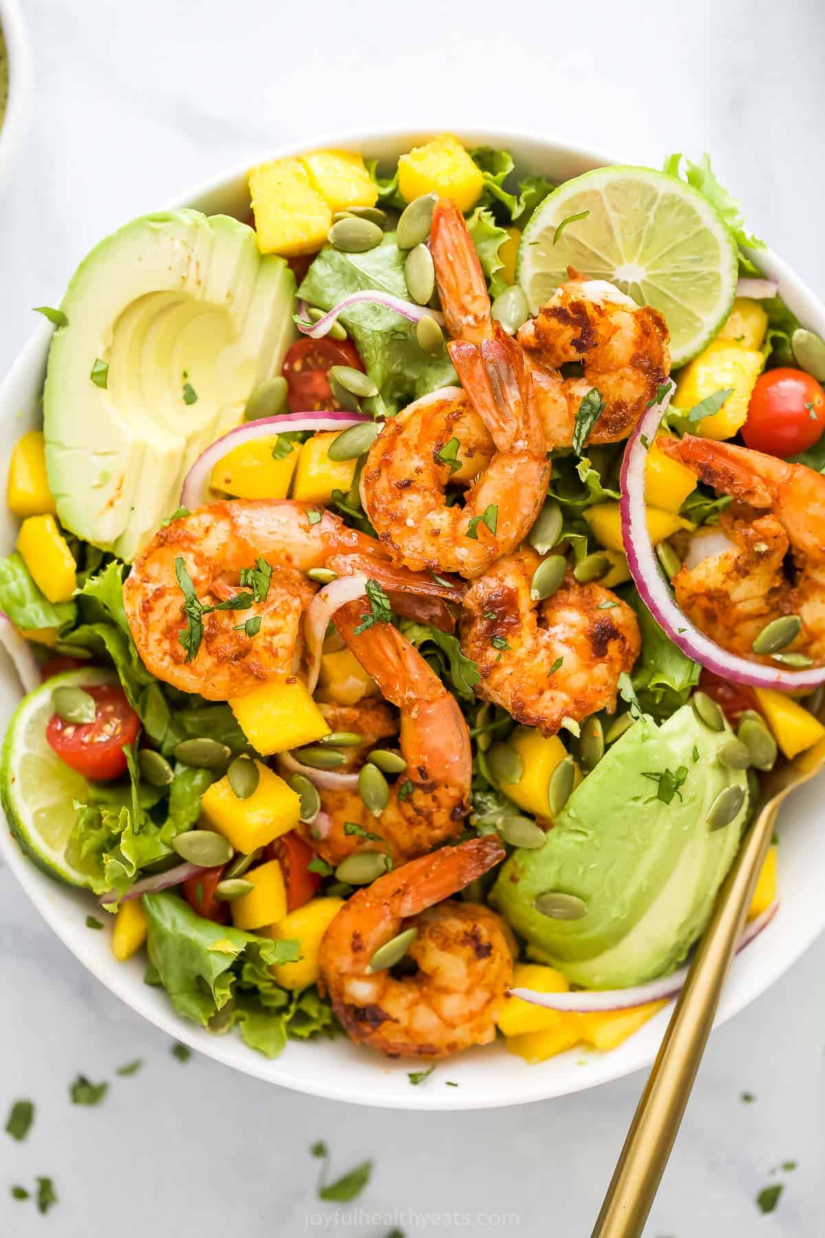 A close-up shot of a tropical shrimp salad in a large white bowl