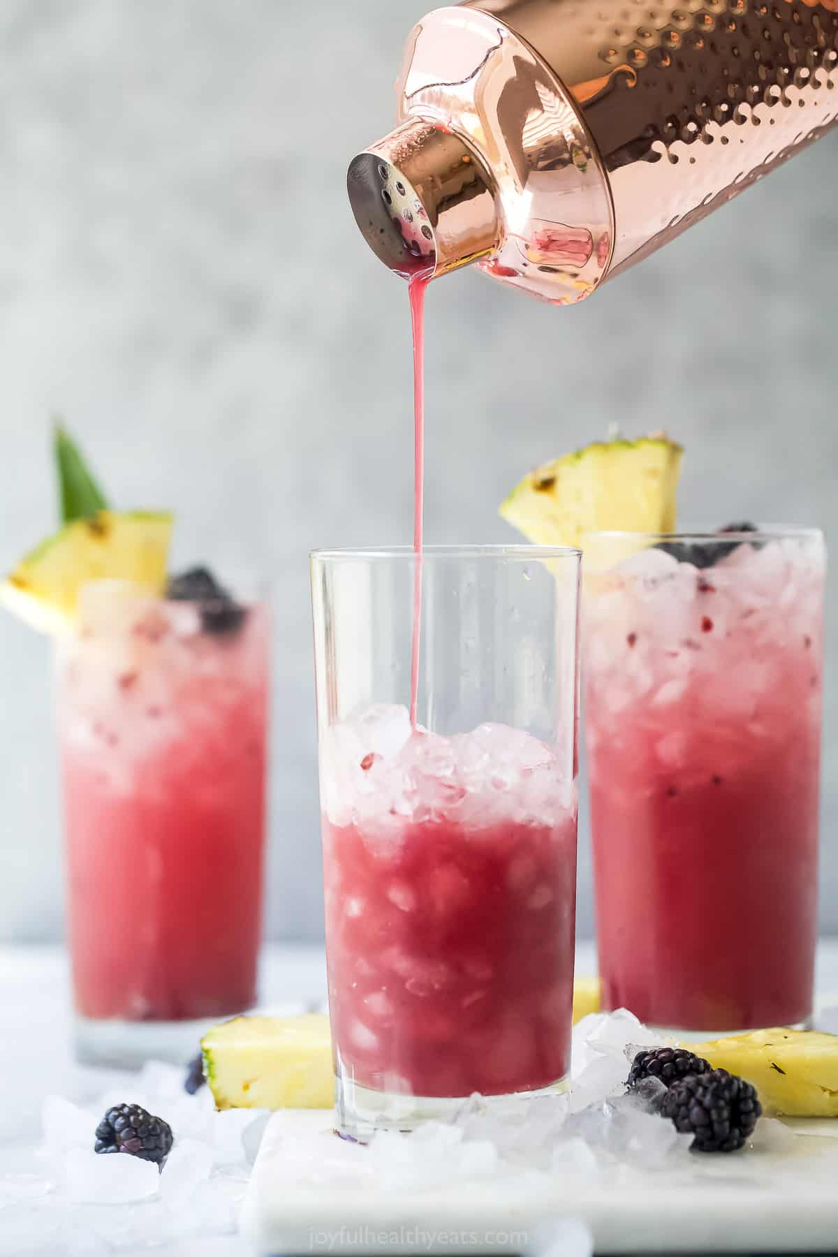 The pineapple mocktail mixture being poured into a glass full of ice