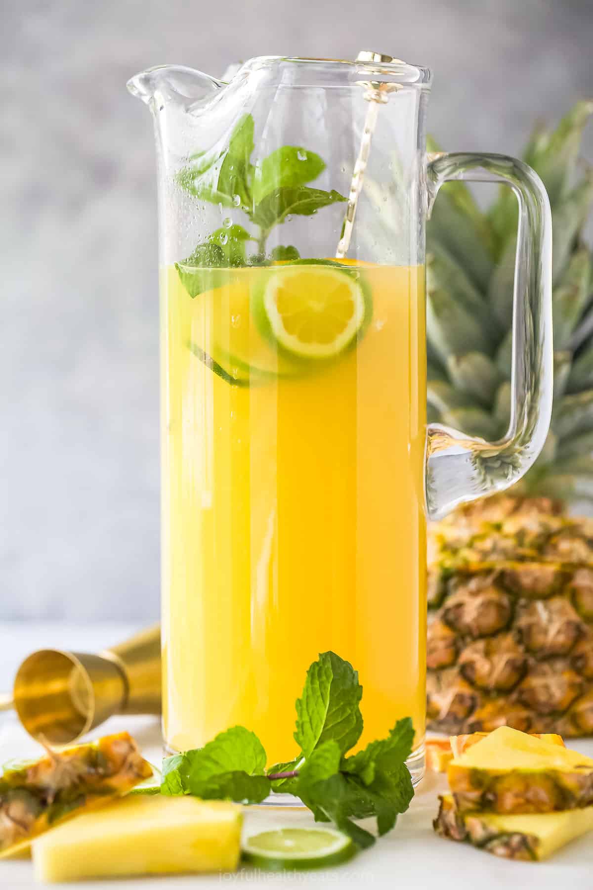 Pineapple rum punch in a tall glass pitcher on a kitchen countertop