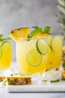 A couple of tropical cocktails on a kitchen countertop with two thin lime slices floating around in each glass