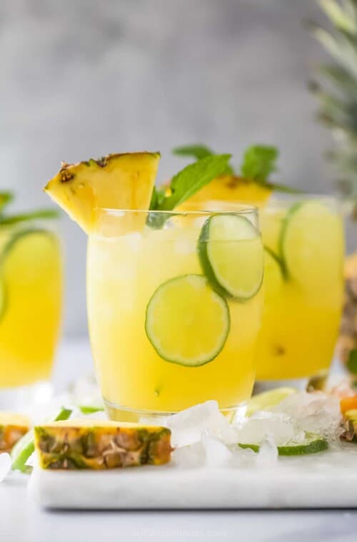 A couple of tropical cocktails on a kitchen countertop with two thin lime slices floating around in each glass