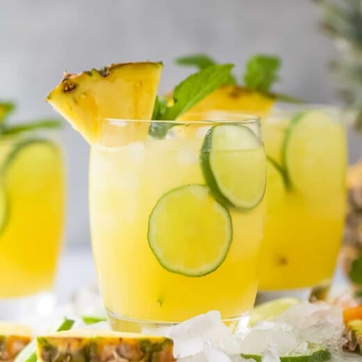 A couple of tropical cocktails on a kitchen countertop with two thin lime slices floating around in each glass