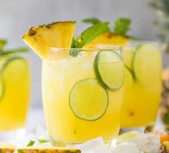 A couple of tropical cocktails on a kitchen countertop with two thin lime slices floating around in each glass