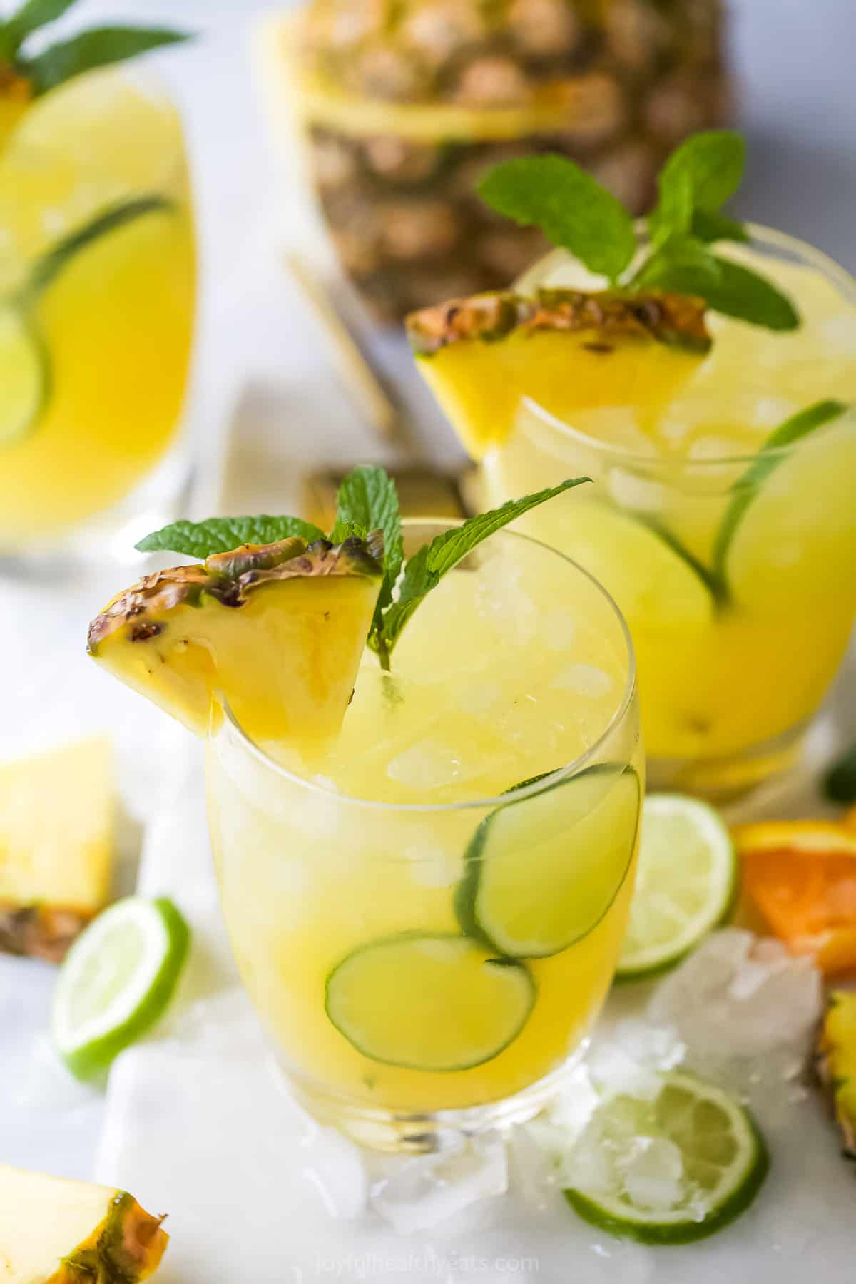 A close-up shot of two pineapple cocktails with a whole fresh pineapple in the background