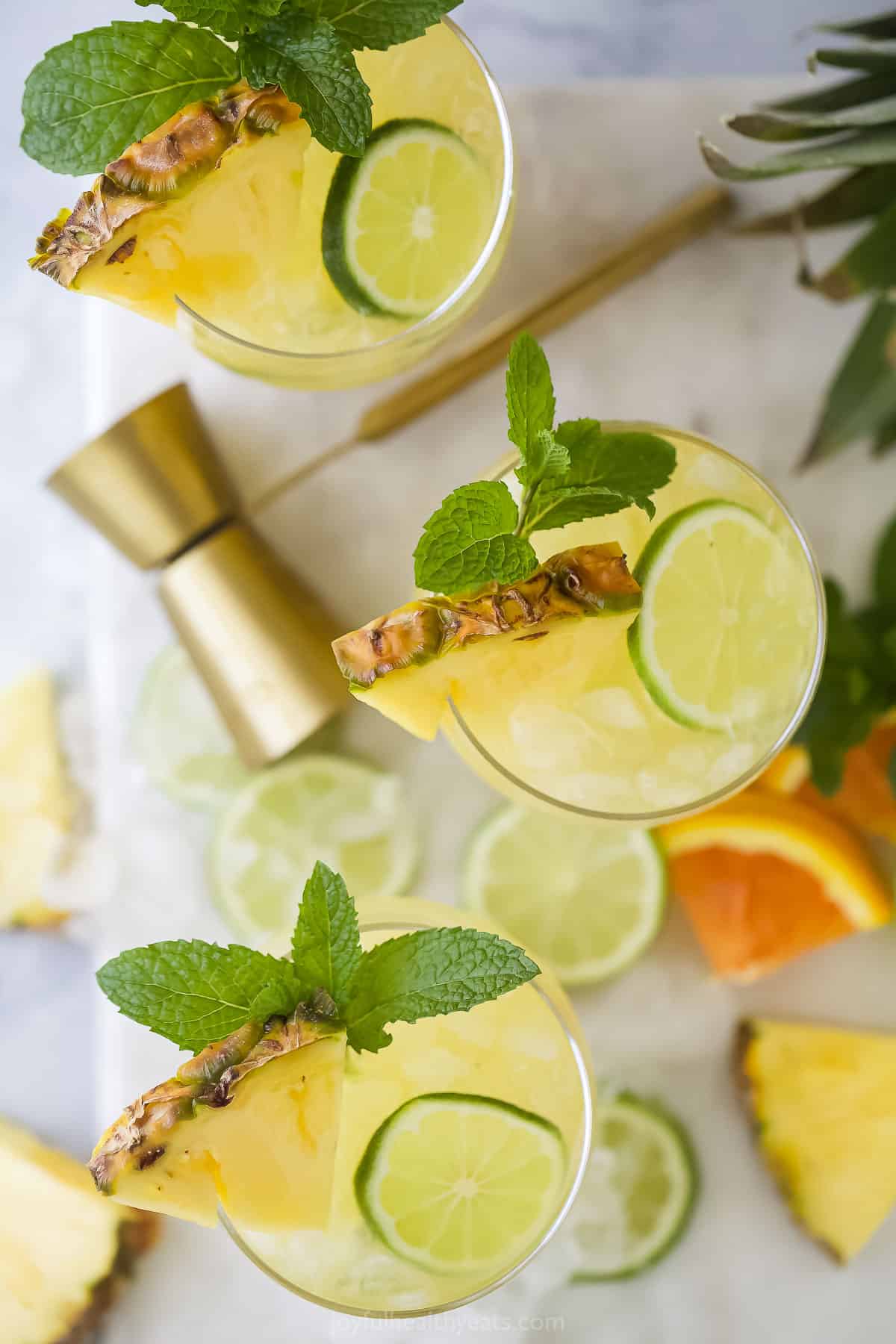 An overhead shot of three pineapple rum punches on a cutting board