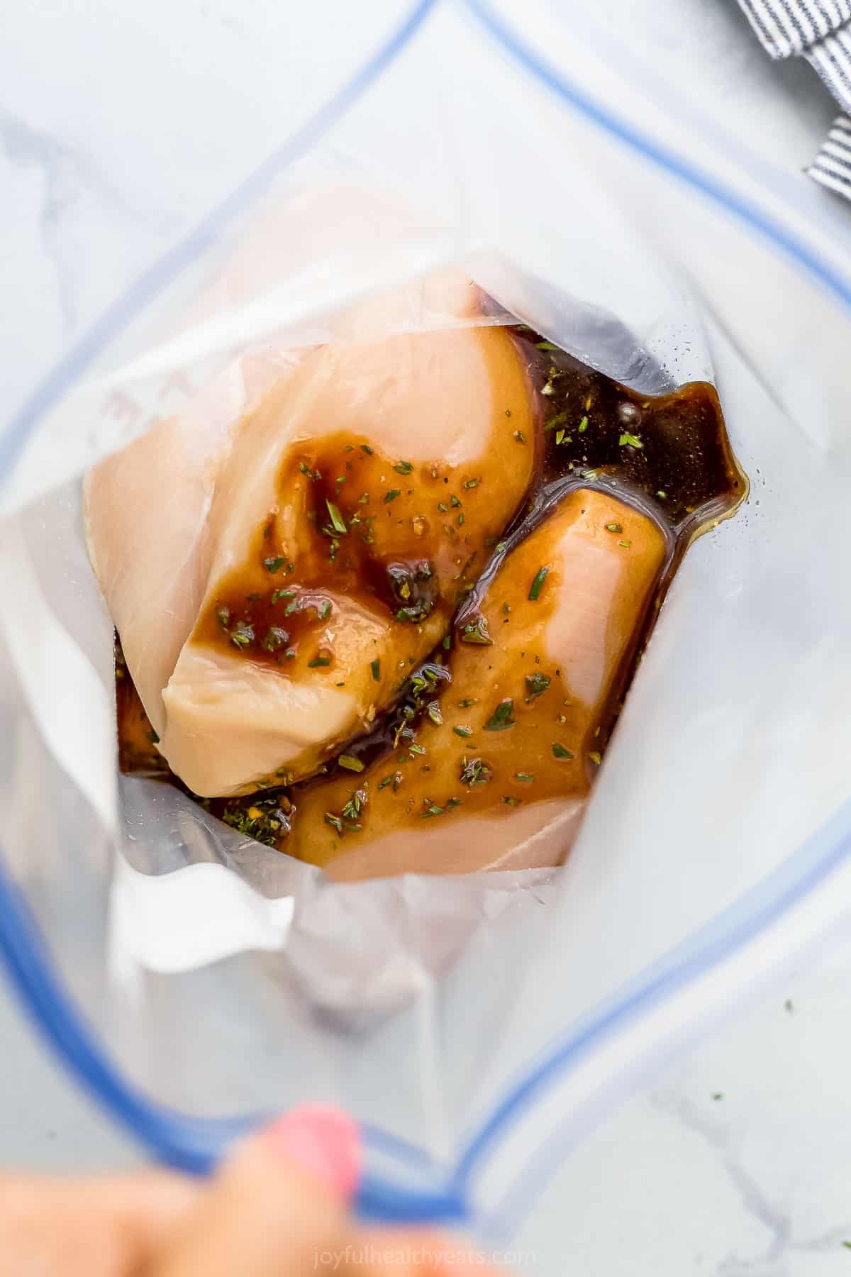 Raw chicken breasts in a Ziploc bag along with the best balsamic marinade