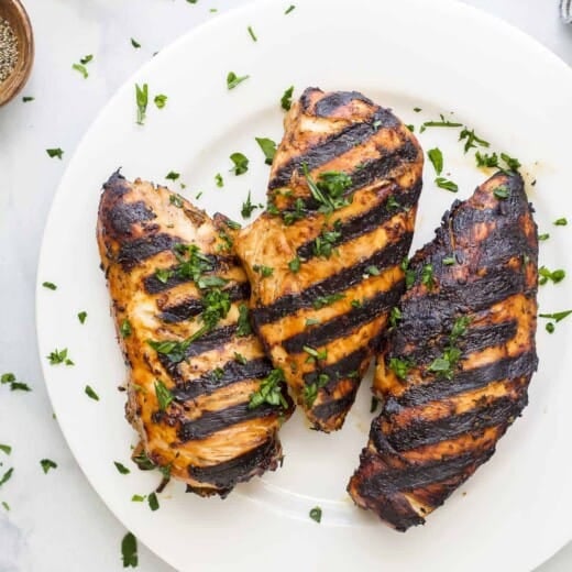 A plate full of balsamic grilled chicken on top of a marble kitchen counter