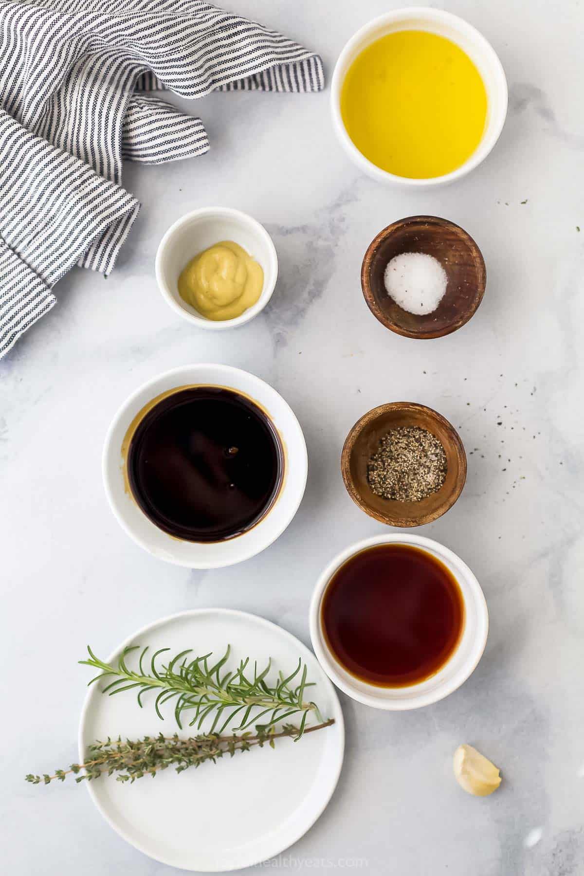 Balsamic vinegar, fresh rosemary, dijon mustard and the rest of the ingredients for the best chicken marinade on a marble countertop