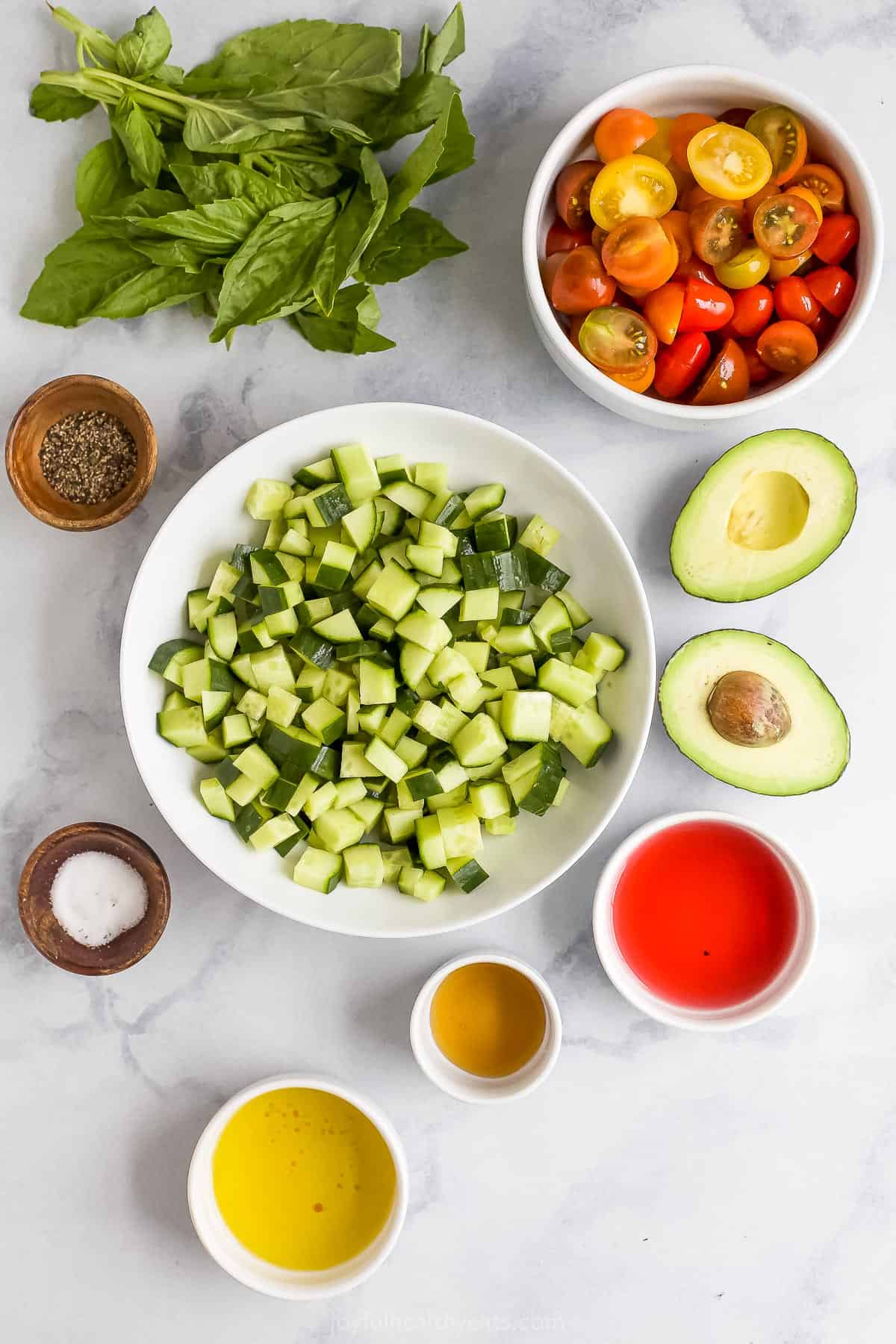 Red wine vinegar, fresh basil, salt, pepper and the rest of the ingredients arranged on a marble countertop