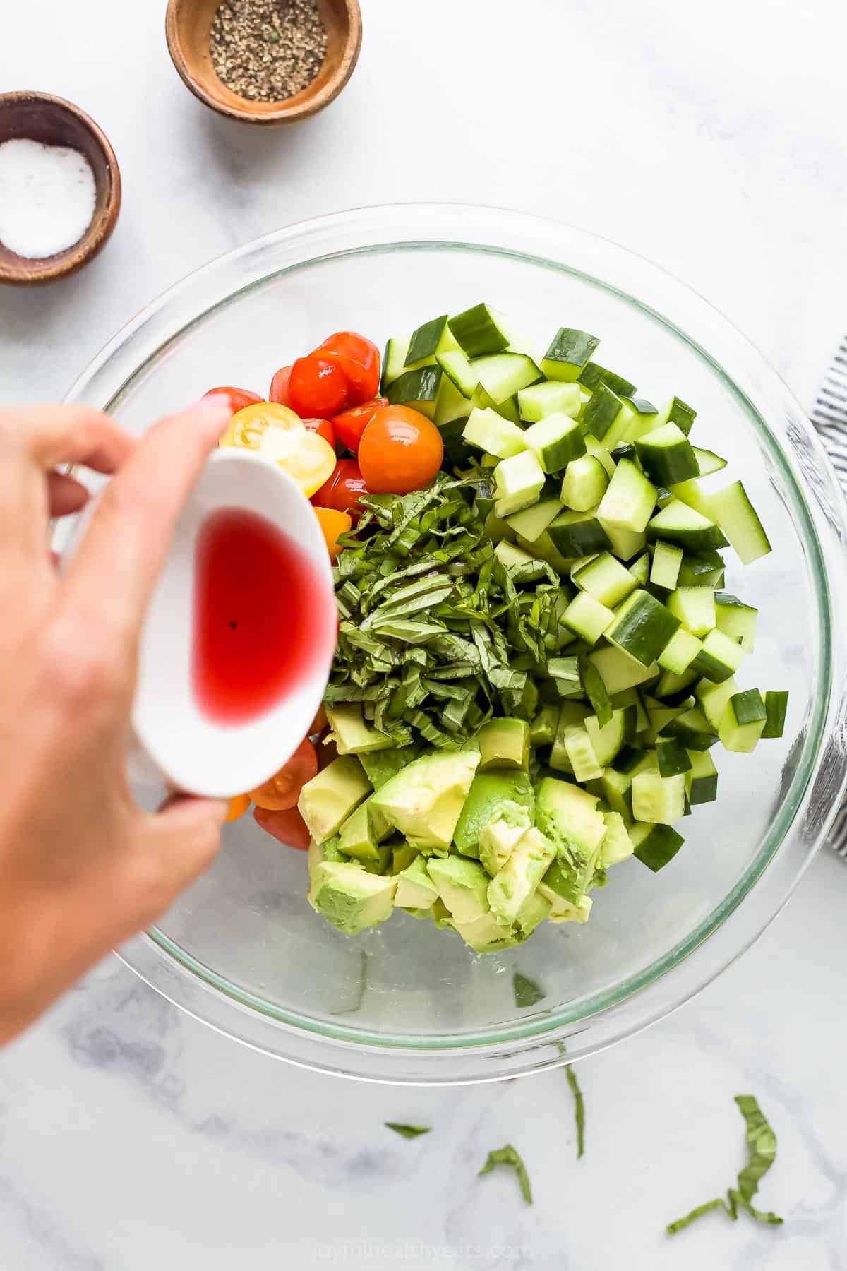 The red wine vinaigrette being poured over the bowl containing the other ingredients