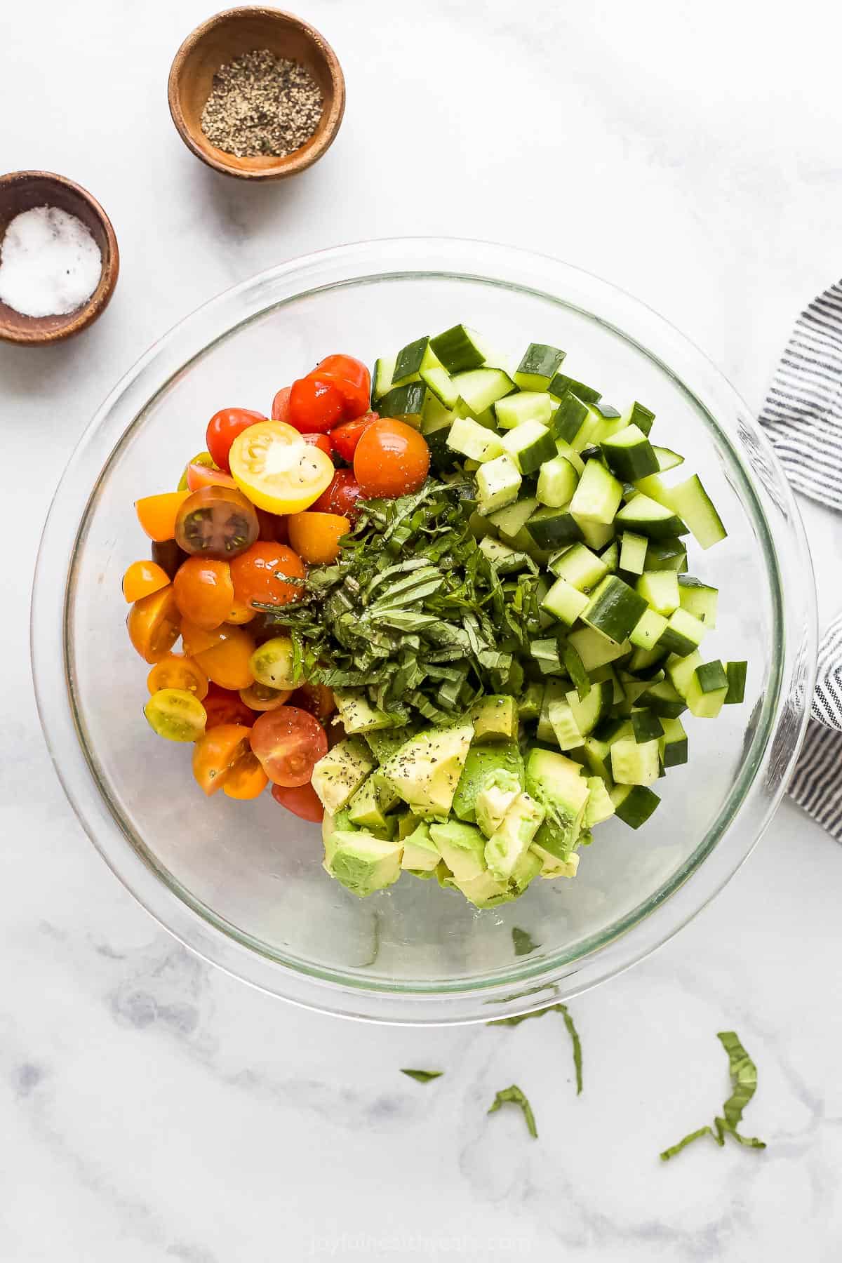 The prepared vegetables in a glass mixing bowl with fresh chopped basil on top