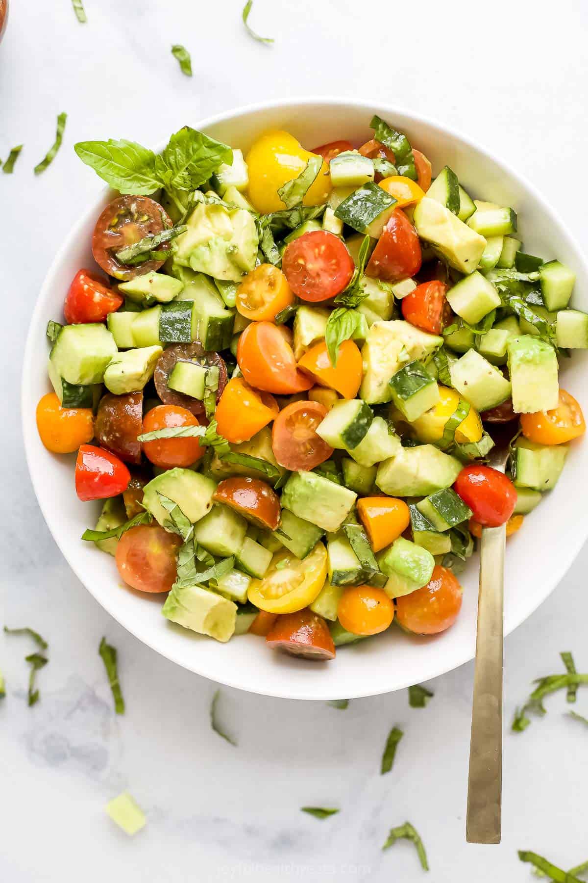 An overhead shot of a bowl of avocado salad with a spoon inside the bowl