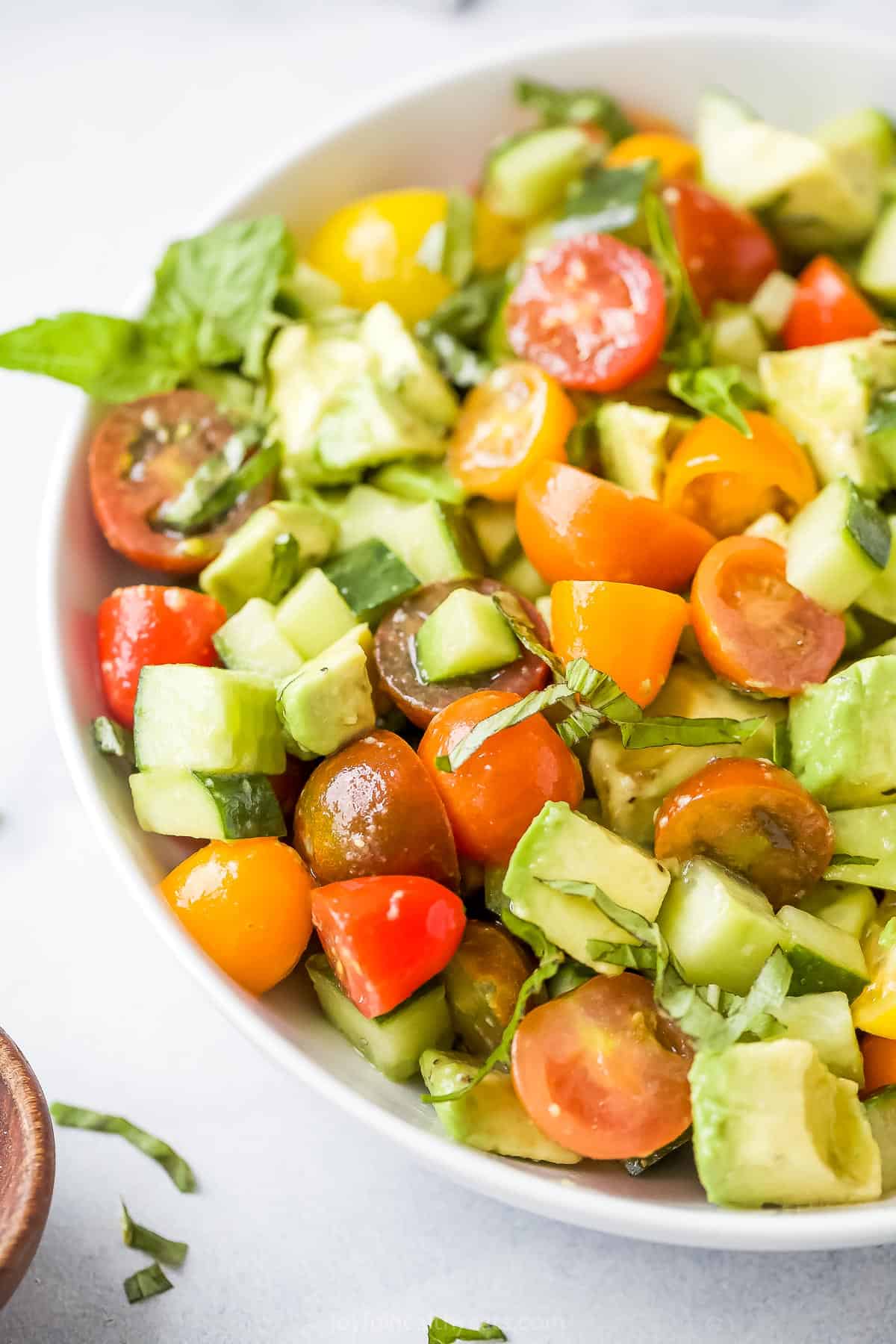 A bowl of avocado tomato cucumber salad on a kitchen countertop