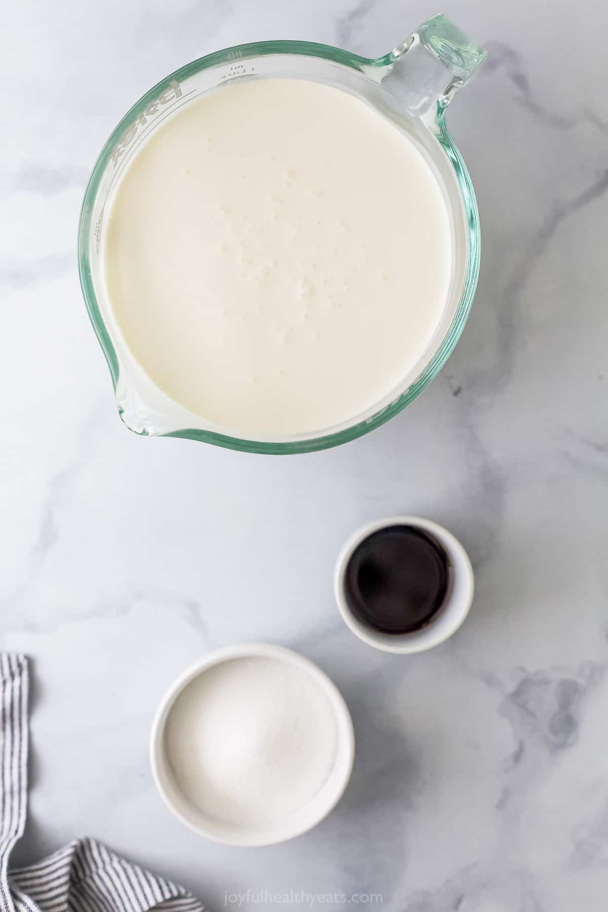 Heavy cream, sugar and vanilla bean paste on a marble kitchen countertop
