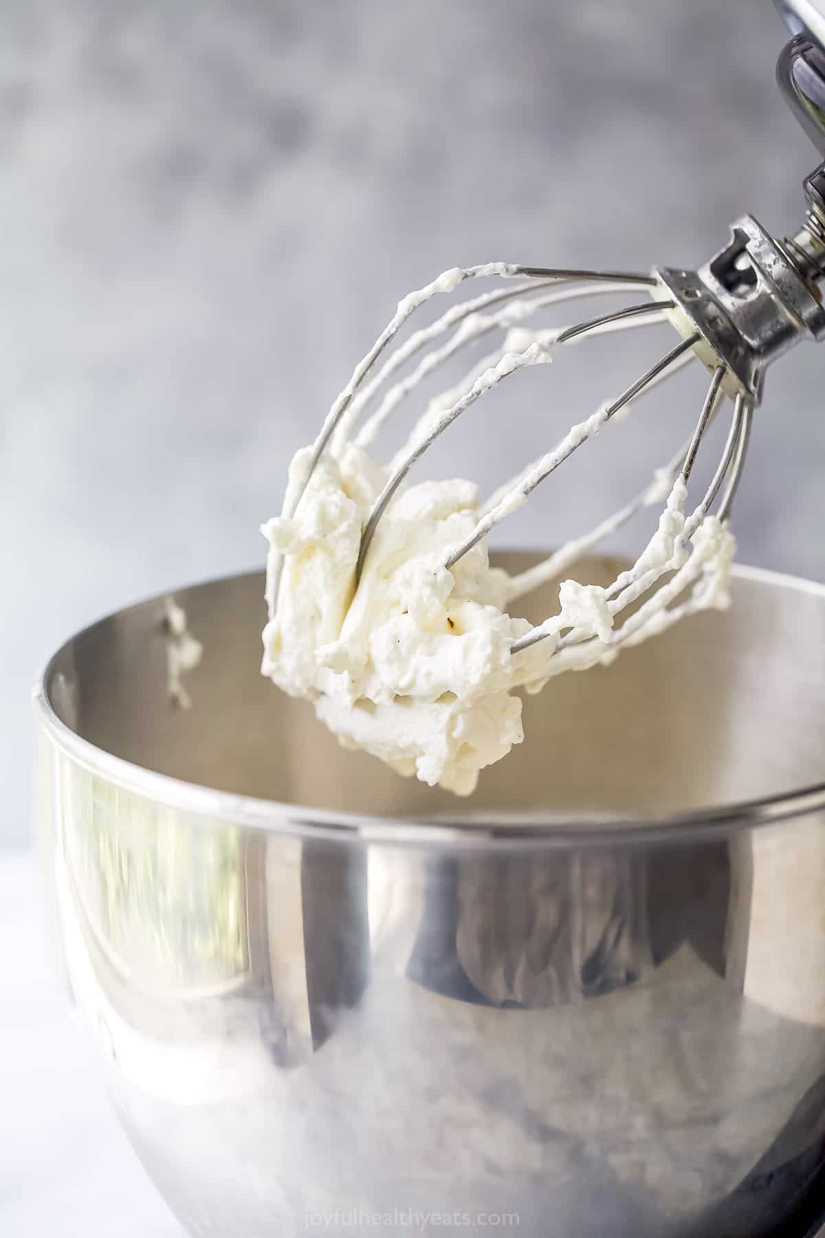 Homemade whipped cream on the whisk attachment of an electric mixer