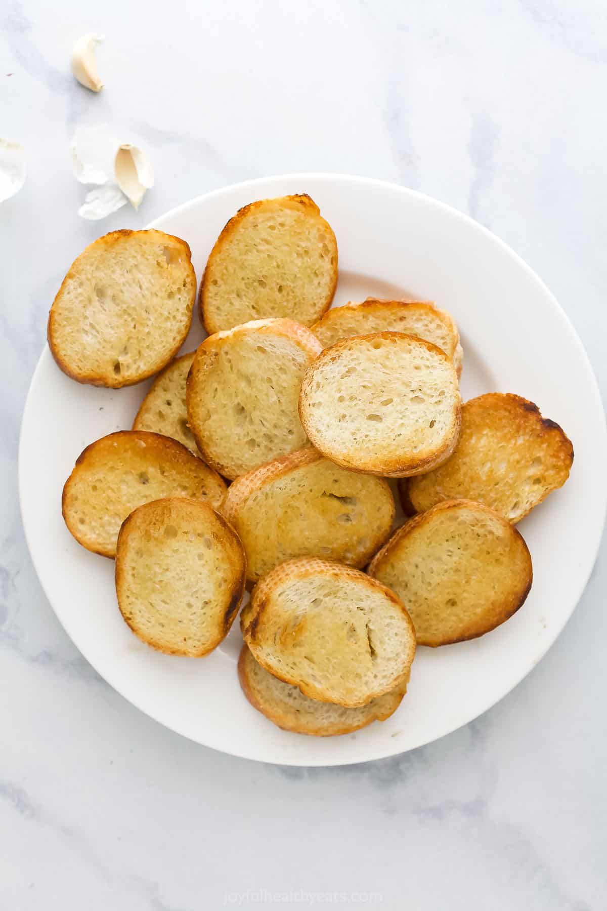 Toasted slices of French bread on a plate on top of a marble surface