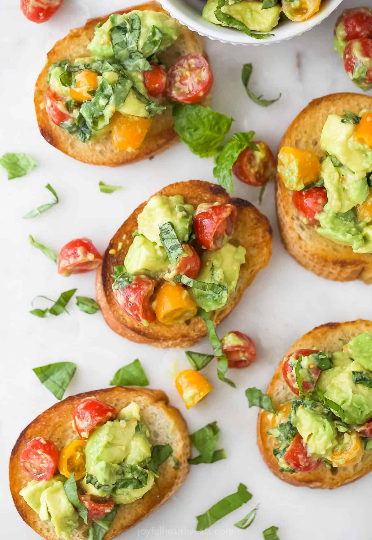 Five pieces of avocado bruschetta bread on a plastic cutting board