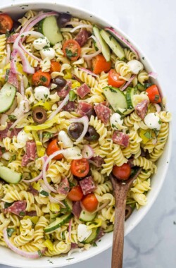 A large white serving bowl full of Italian pasta salad