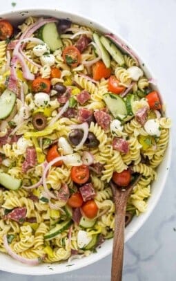 A large white serving bowl full of Italian pasta salad