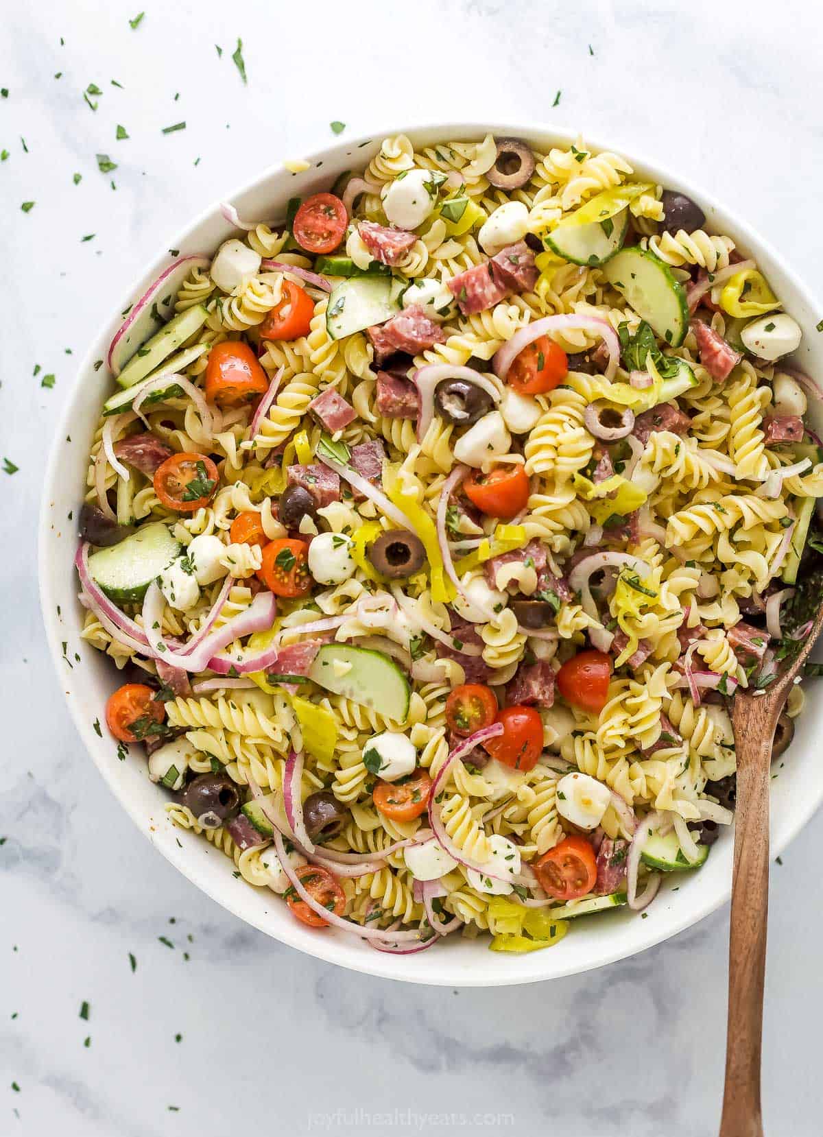 One big bowl of Italian pasta salad placed on top of a marble surface