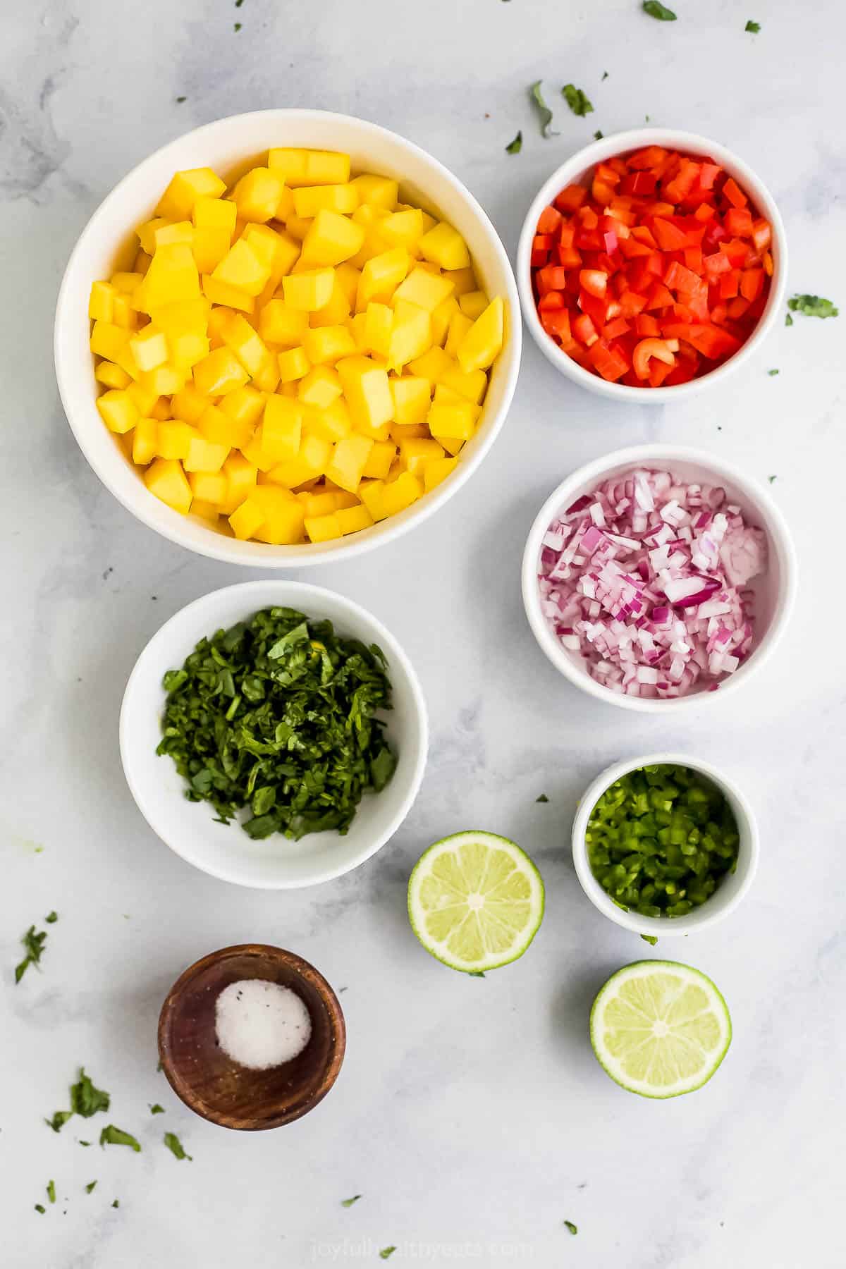 A fresh lime, diced jalapeño, salt and the rest of the ingredients arranged on a marble surface