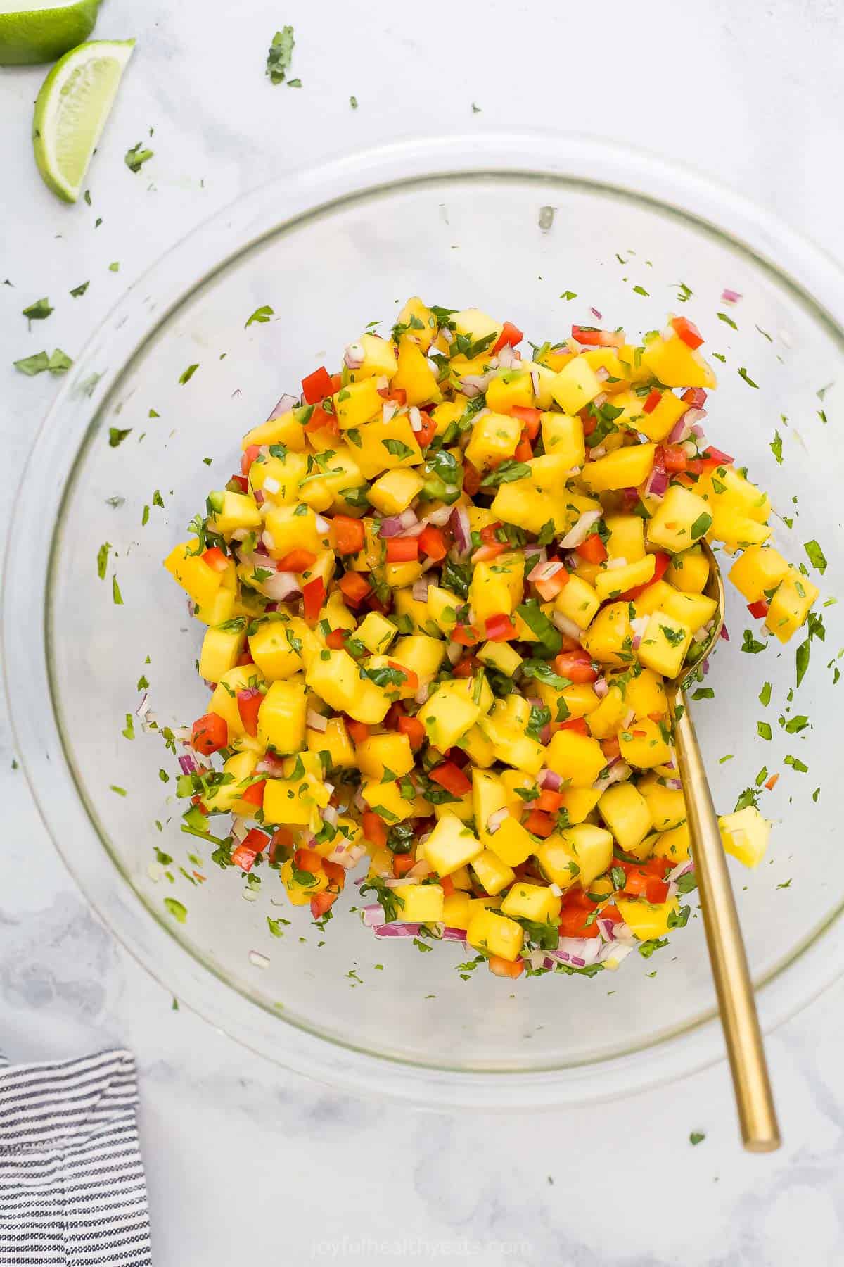 Mango salsa being mixed inside of a large glass bowl
