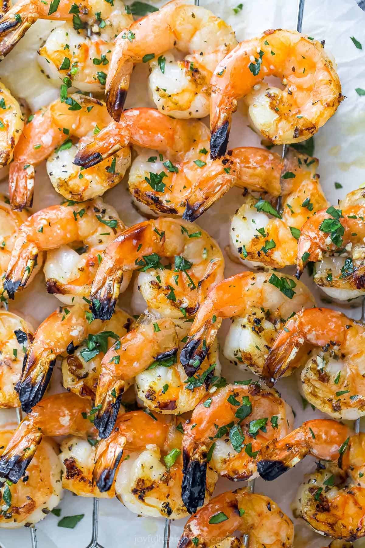 A close-up shot of garlic lemon shrimp threaded onto metal skewers