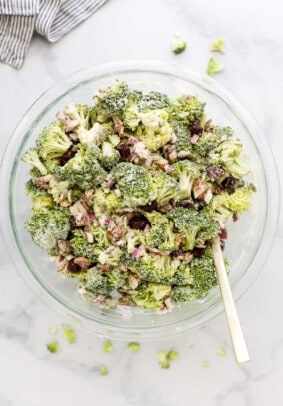 The dressing and salad being mixed together in a big glass bowl