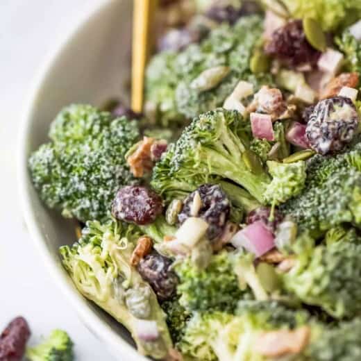 A close-up shot of broccoli salad with dried cranberries in a large serving bowl
