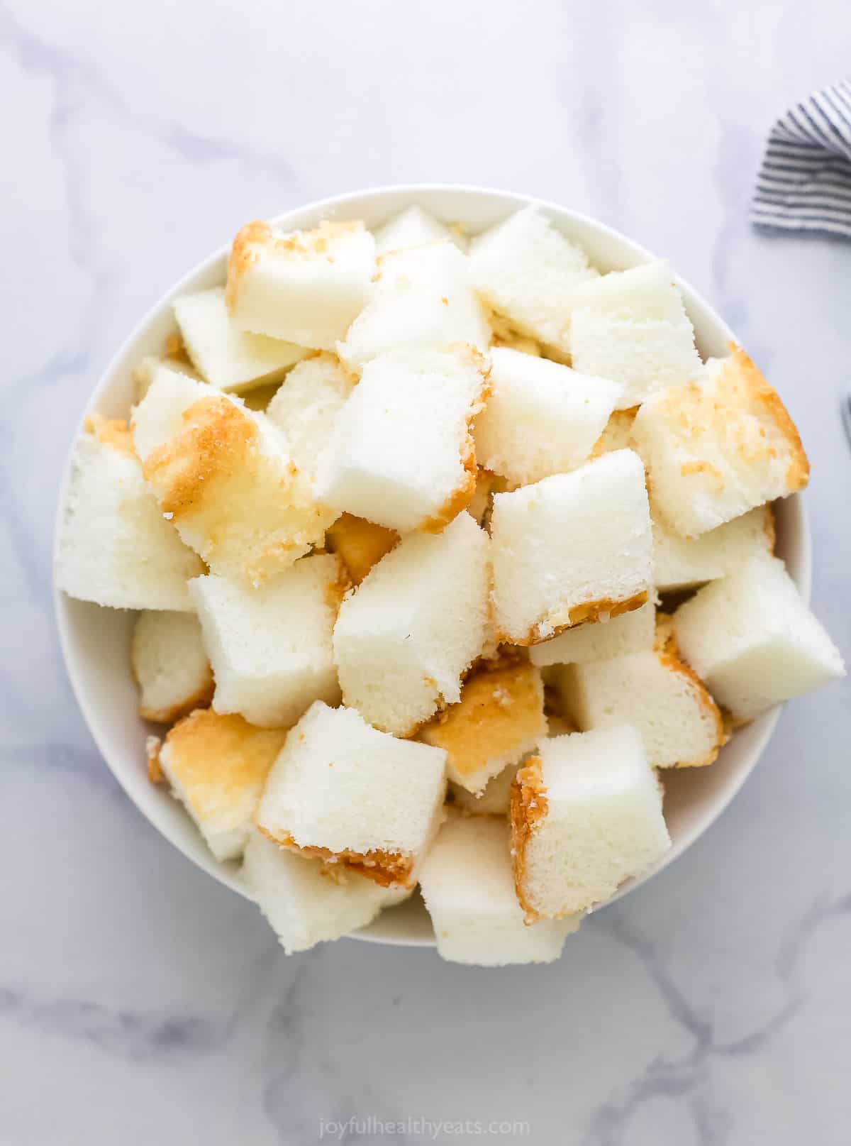 Cubes of angel food cake in a bowl on a marble countertop