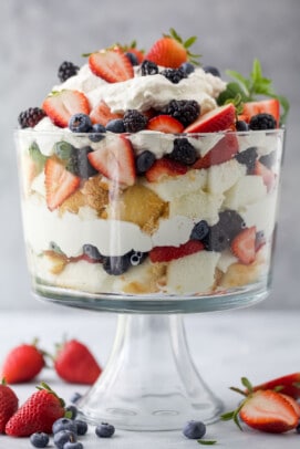 A large trifle dish with layers of angel food cake, fresh berries and homemade whipped cream inside
