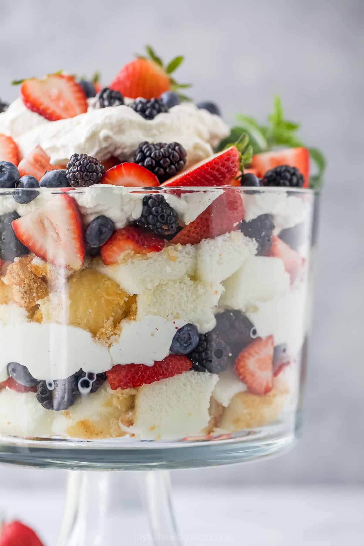A strawberry blueberry blackberry trifle inside of a large trifle bowl