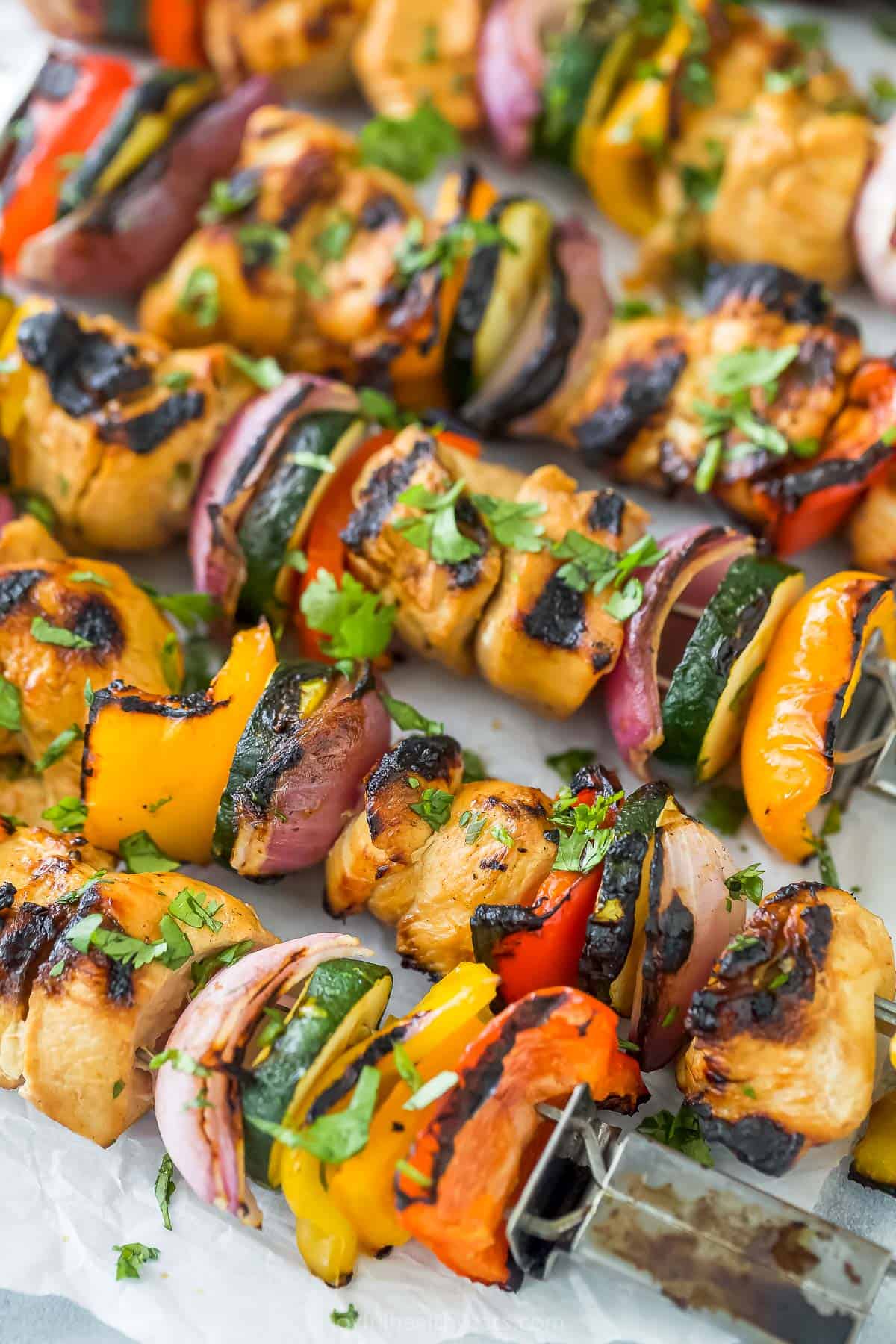 A close-up shot of grilled chicken kabobs with chopped parsley sprinkled on top