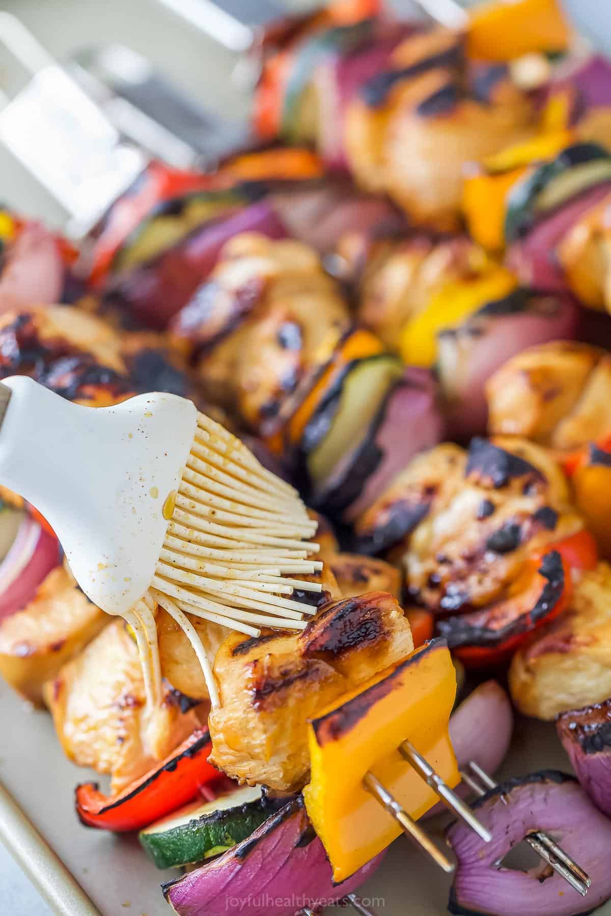 Reserved pineapple marinated being brushed over kabobs about halfway through the grilling process