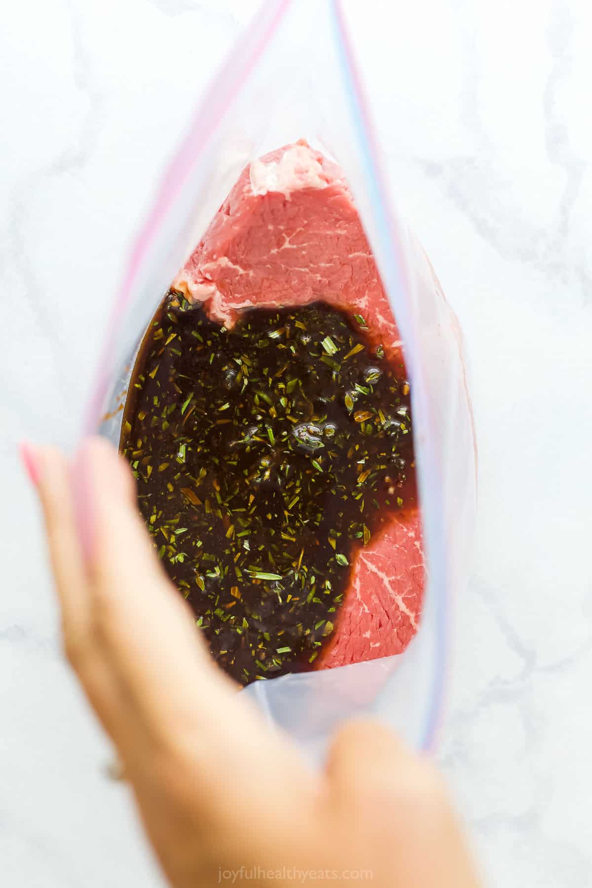 Raw steak inside of a large Ziploc bag with the marinade poured over it