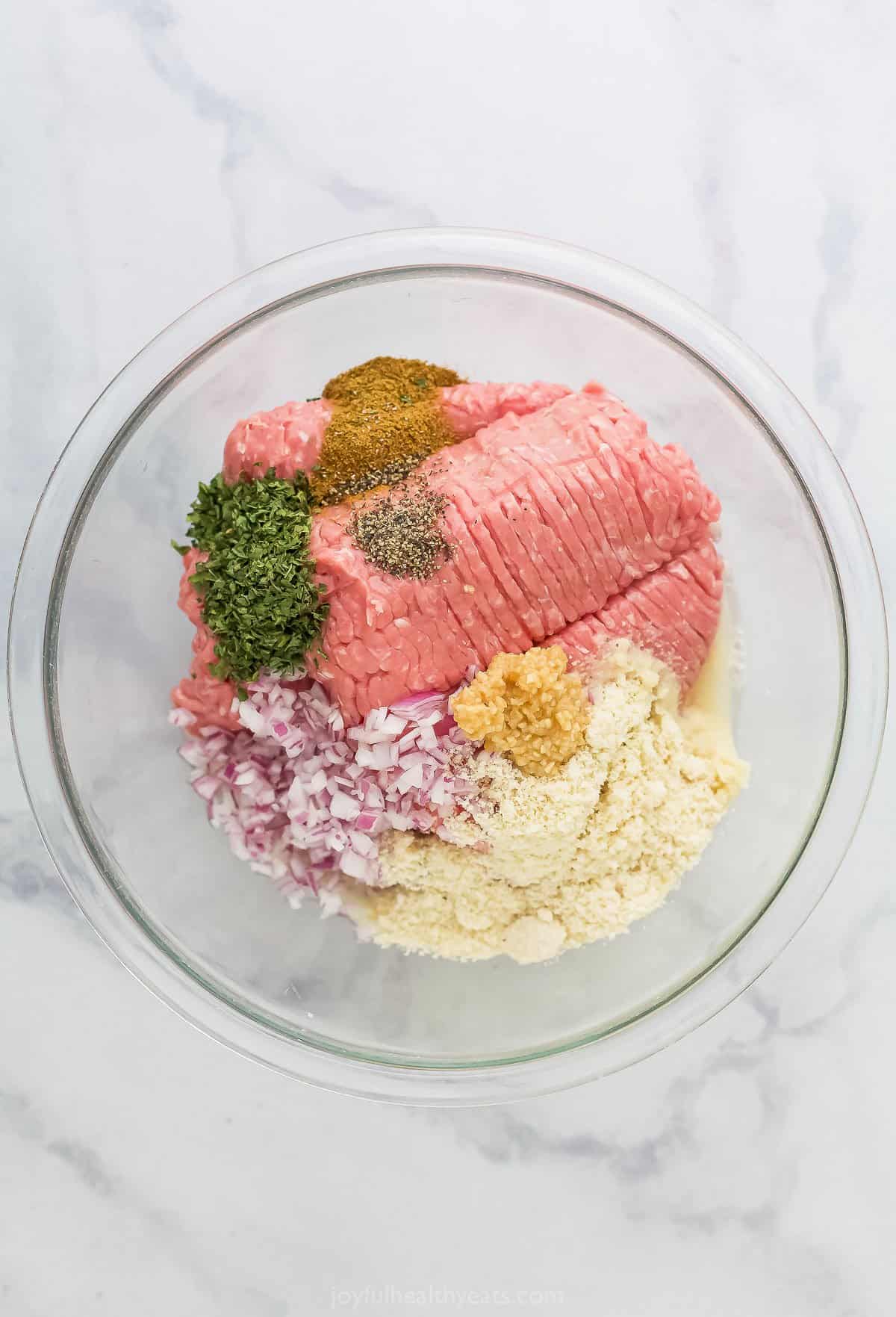 Ground turkey in a large mixing bowl with dried parsley, diced red onion and the remaining patty ingredients