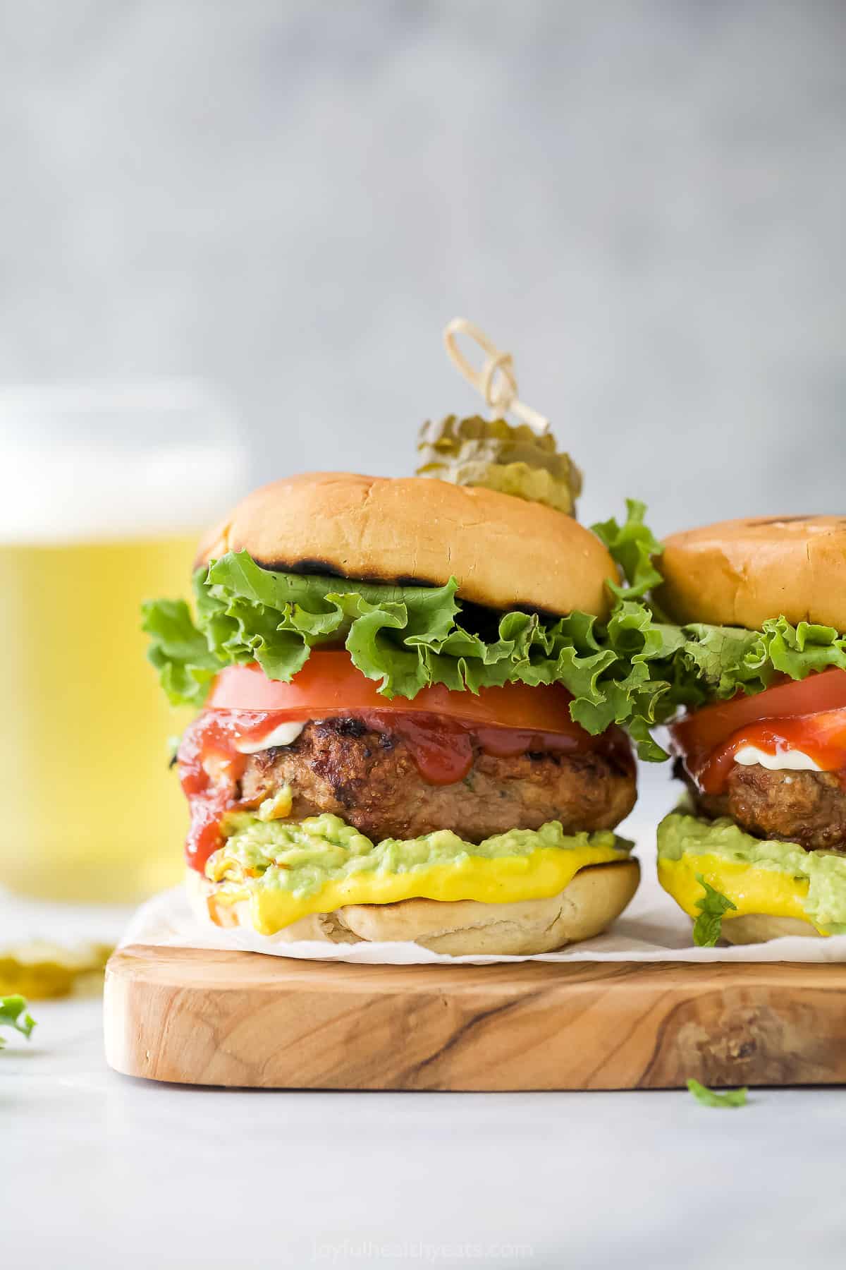 A homemade burger on a kitchen countertop with a beverage in the background