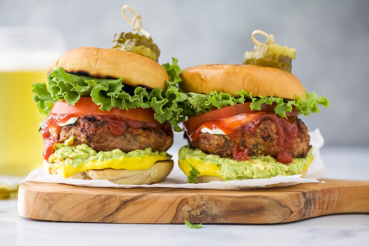 A close-up shot of two homemade turkey burgers with toothpicks stuck in the tops to help hold them together