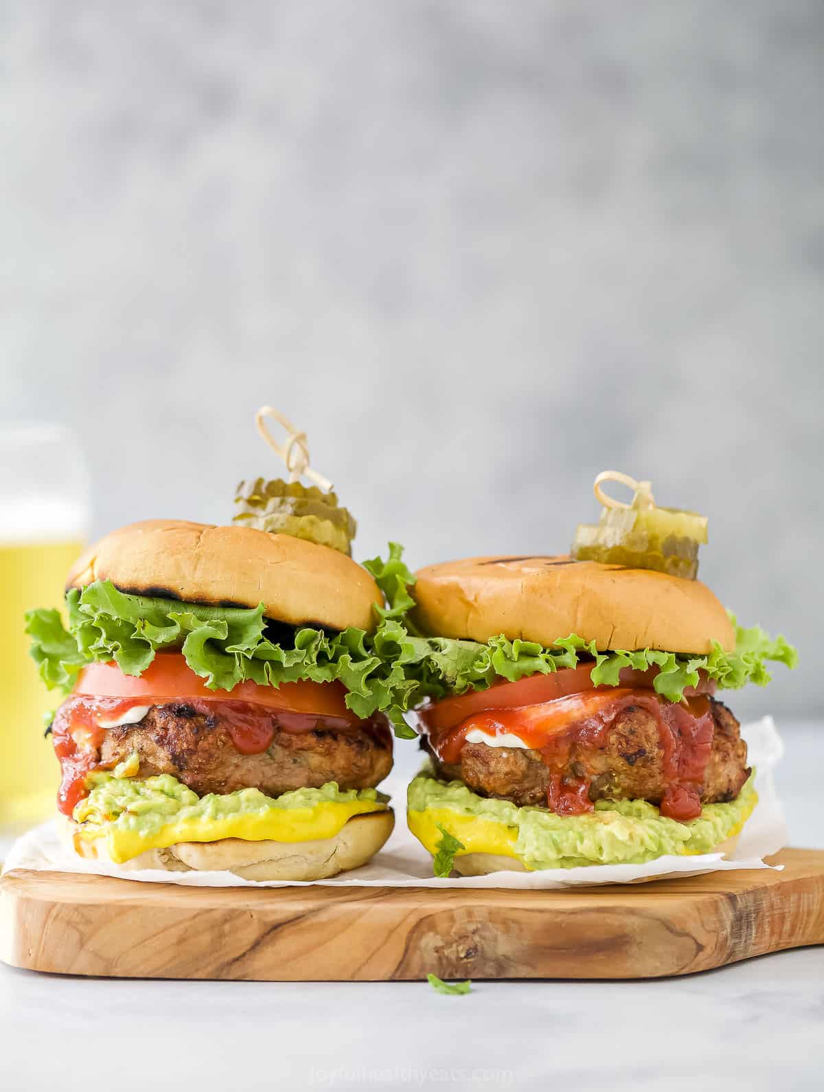 Two turkey burgers with homemade patties sitting side-by-side on a cutting board