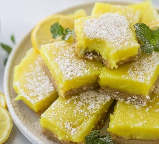 A batch of vegan lemon bars piled onto a plate with a raised rim