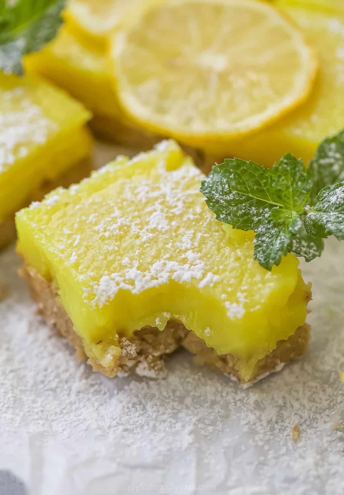 A close-up shot of a lemon square with a bite taken out of it