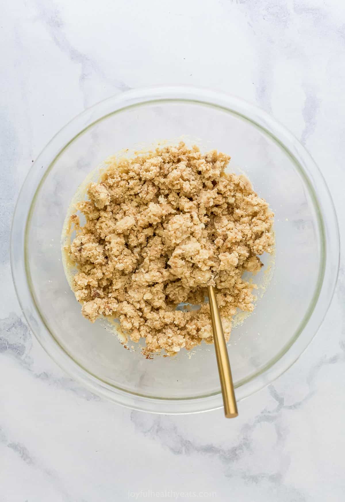 The combined crust mixture in a glass mixing bowl sitting on a marble surface