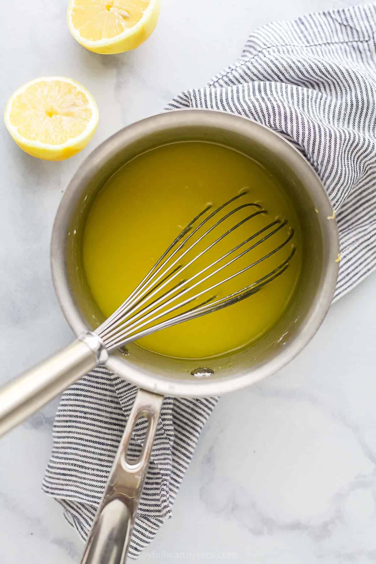 The lemon curd filling being whisked in a metal saucepan on top of a striped dish towel